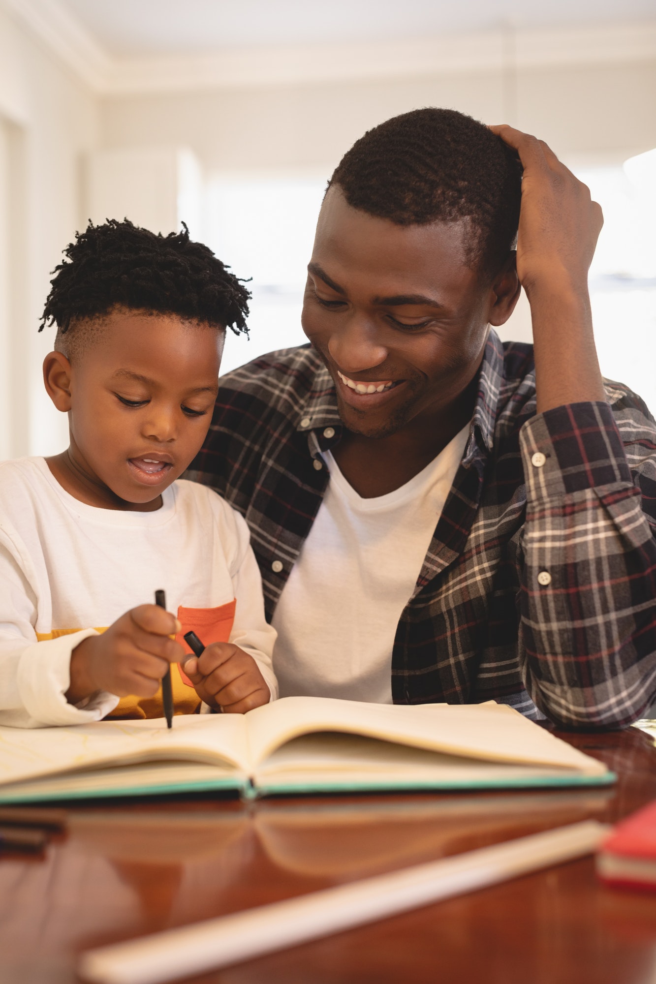 Front view of African American father helping his son with homework at table